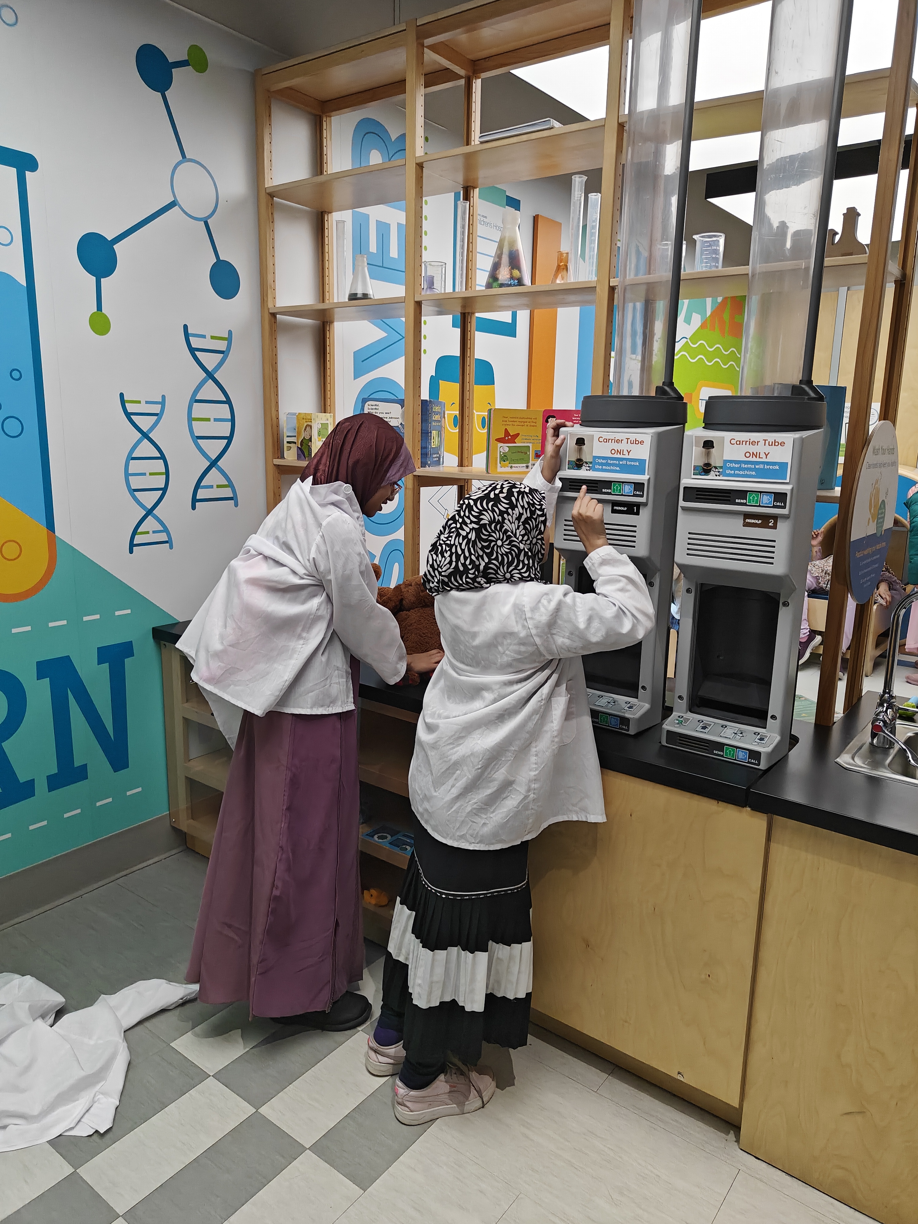 Students in lab coats exploring a science exhibit